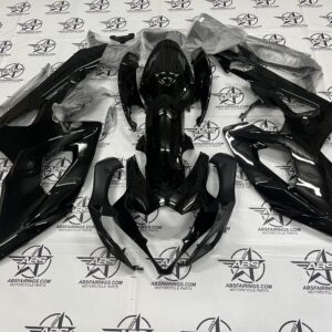 Black motorcycle body fairings laid out on floor.