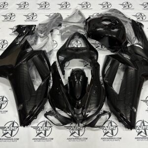 Glossy black motorcycle fairing set on branded mat.