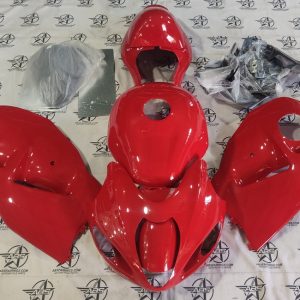 Red motorcycle fairings set displayed on floor.