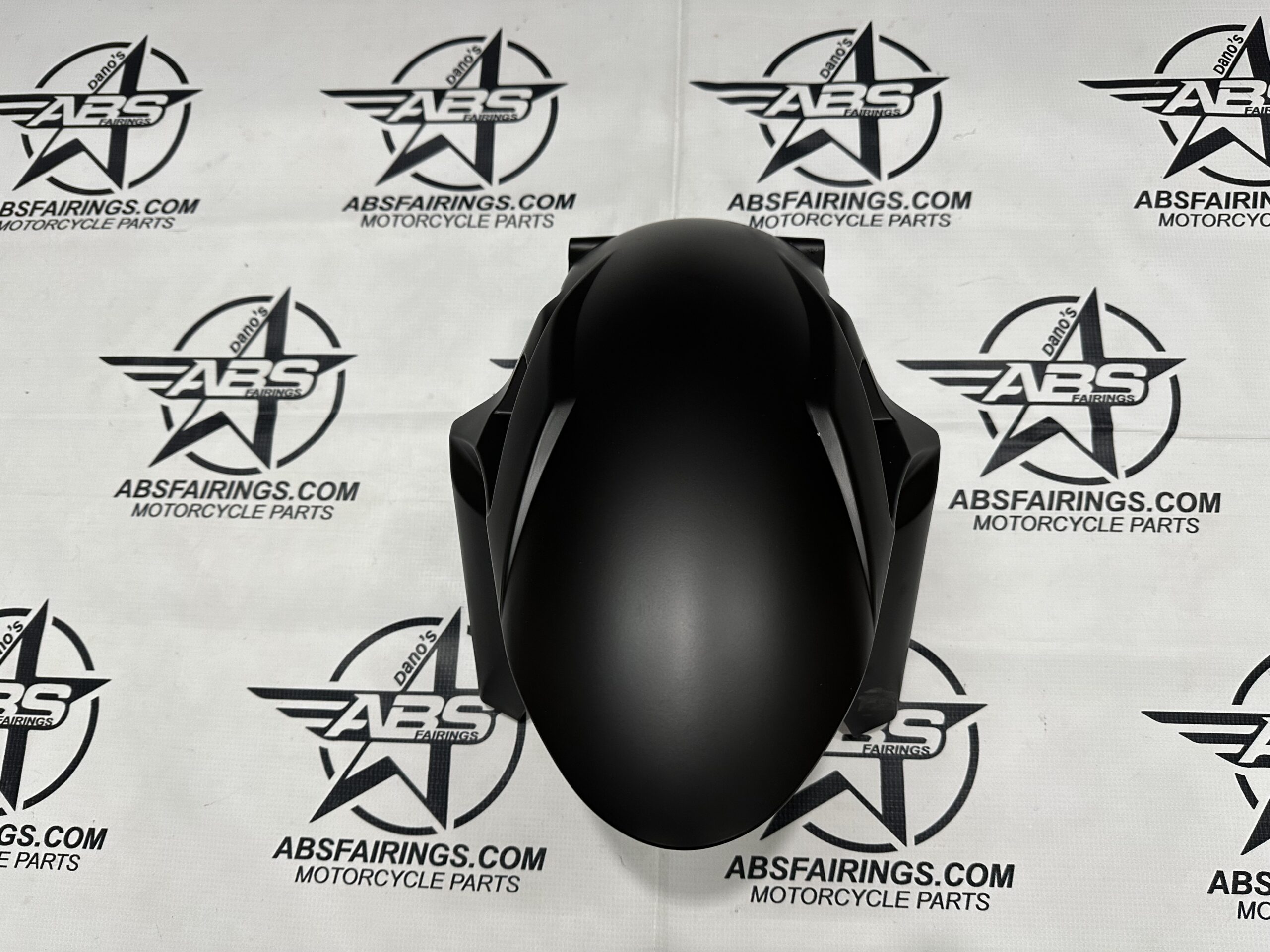 Matte black motorcycle fairing on branded background.