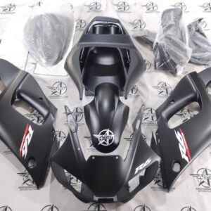 Black motorcycle fairing kit displayed on floor.